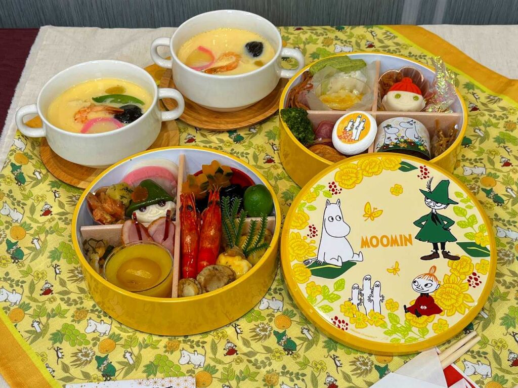 ムーミンおせち 二段重｜黄色い丸型重箱とリトルミイやスナフキンの料理