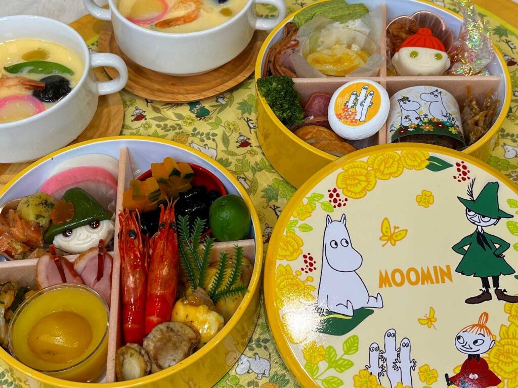 ムーミンおせち 二段重｜黄色い丸型重箱とリトルミイやスナフキンの料理